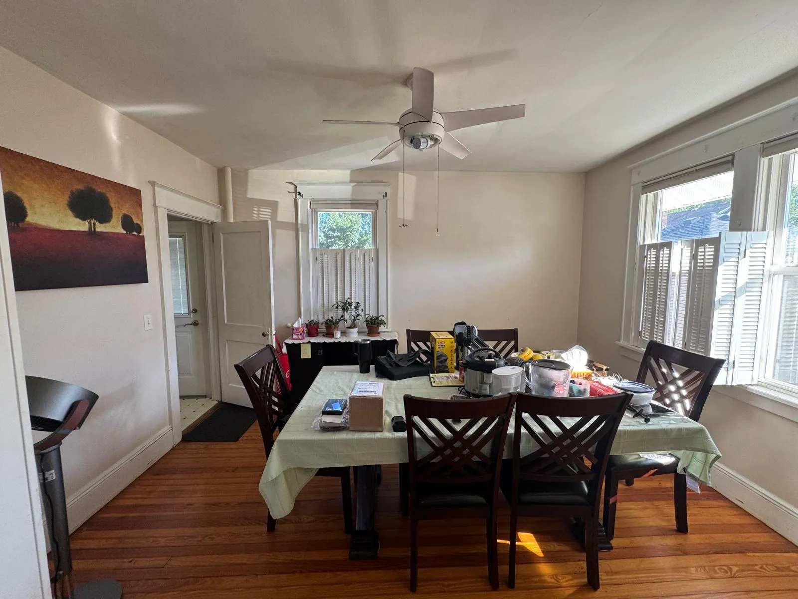 Dining room before restyling: dining before, wide: table covered with small appliances; floor fan.