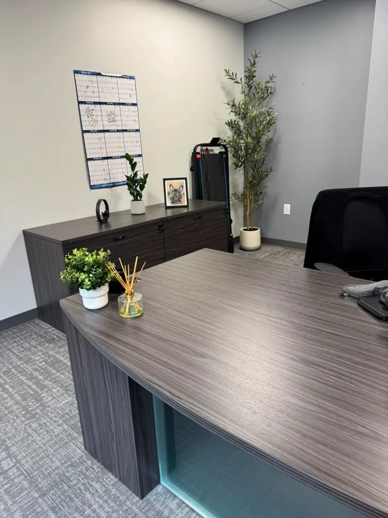 Office after restyling by Kultur & Decor: styled desk/credenza corner: calendar, olive tree, reed diffuser (portrait).