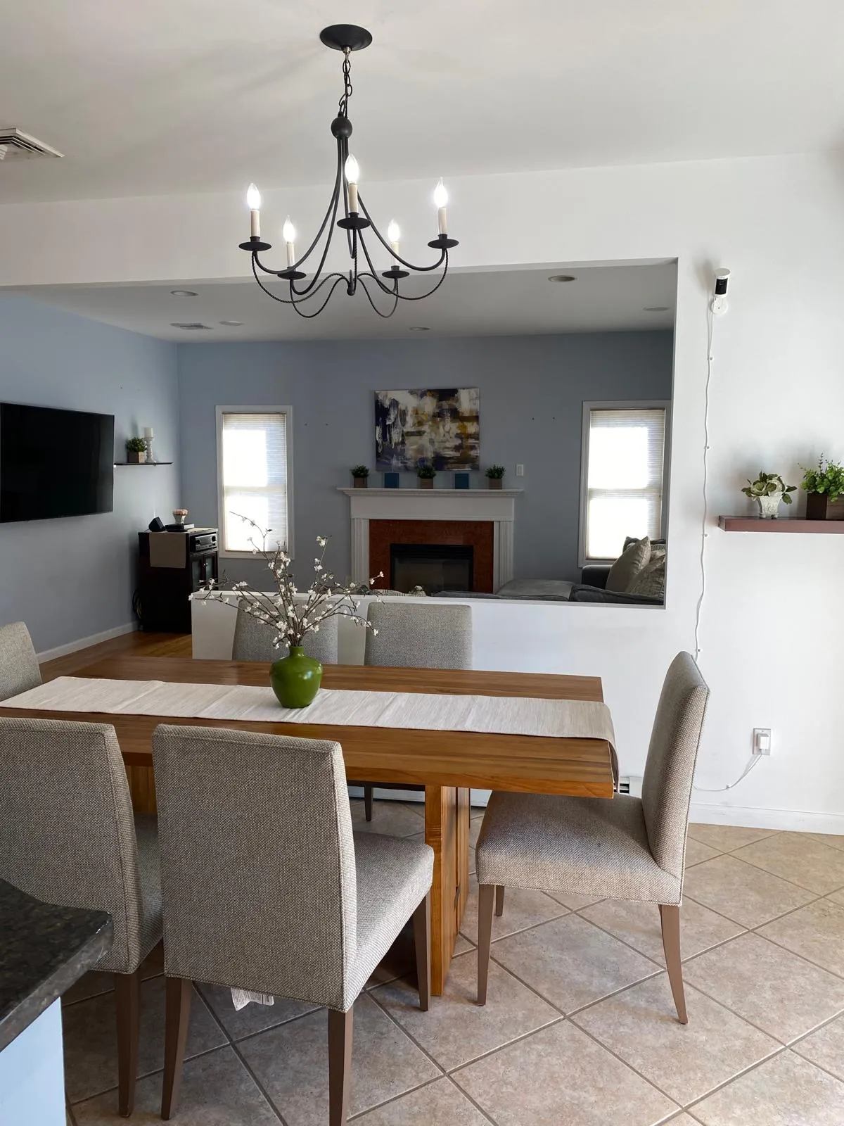 Kitchen/dining room after restyling by Kultur & Decor: looking through to the family room: runner and blossom centerpiece, hearth and canvas framed by the opening.