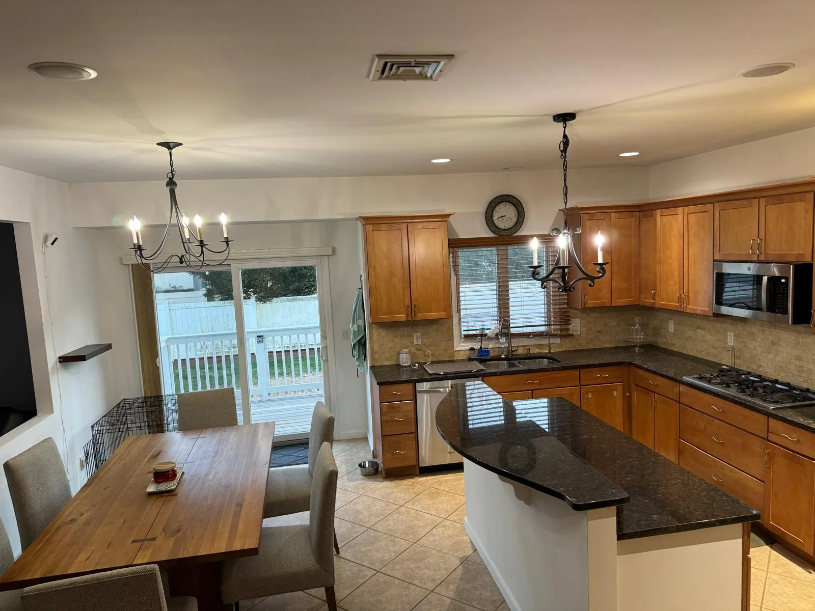 Kitchen/dining room before restyling: wide: dog crate, coats on the door hook, bare table, both chandeliers on. Shares its after with residence2-kitchen-before-01 (same room, further back).