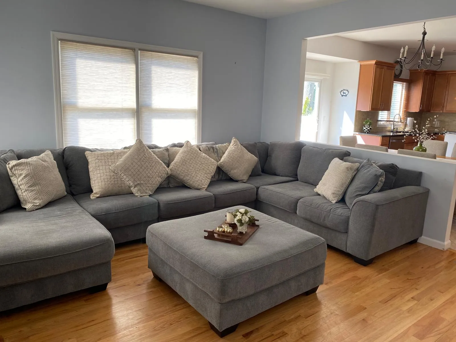 Family room after restyling by Kultur & Decor: landscape: sectional and ottoman anchored, sightline open through to the kitchen.