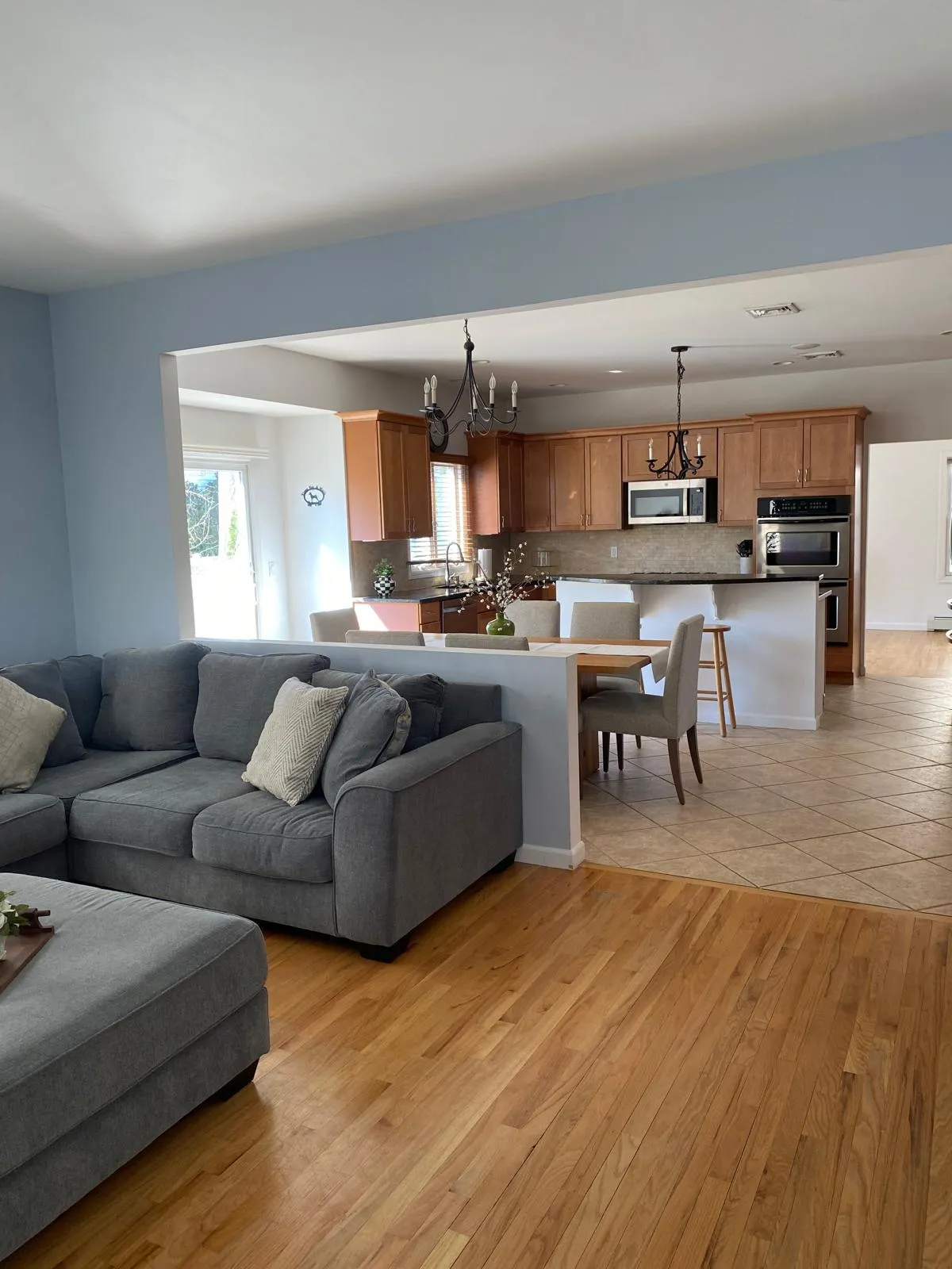Family room after restyling by Kultur & Decor: looking through the half-wall to the dining table and kitchen beyond; shows the open-plan flow.