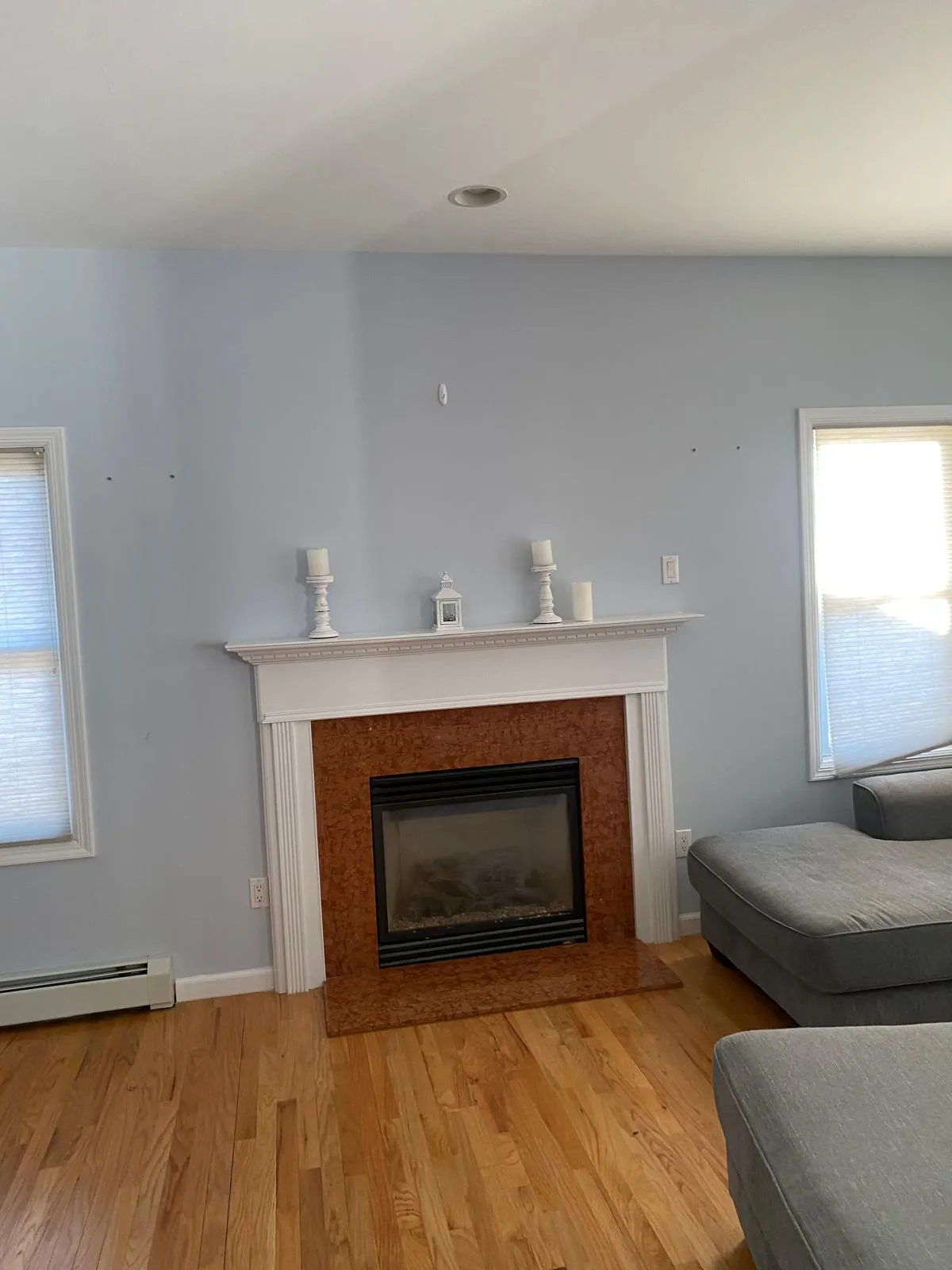 Family room before restyling: bare mantel with stray candles and a lantern, sectional pushed to the wall.